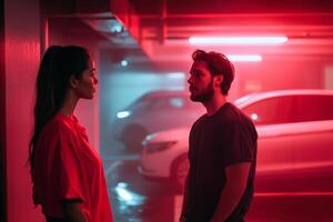 Couple in a dimly lit parking garage sharing an intimate moment under neon red lights during the evening hours photo