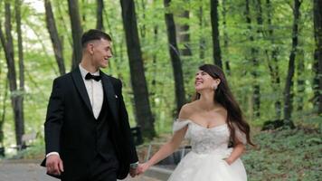 Happy Bride and Groom Walking in Forest, Smiling bride and groom walk hand in hand through a lush green forest video