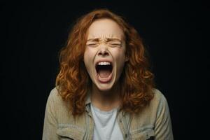 A woman with red hair screaming on a black background photo