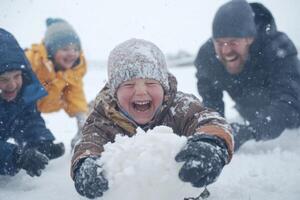 Children joyfully play in the snow, building snowballs and laughing with adults on a snowy winter day photo