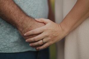 A couple holding hands tightly, creating a moment of affection in a serene outdoor setting photo