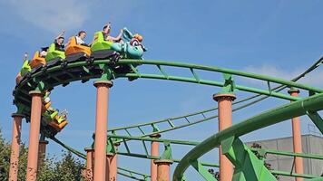 Poland, Zator 28.09.2024 Colorful Roller Coaster Ride in Action, Brightly colored roller coaster with excited passengers twists along green tracks under a blue sky in a lively amusement park video