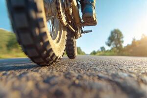 Close-up of a motorcycle tire on a winding road during sunset, highlighting the thrill of adventure on an open stretch of countryside photo
