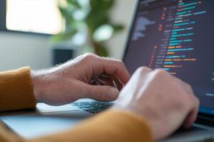 A person coding on a laptop at home during the day, focusing on the screen in a well-lit workspace with plants photo