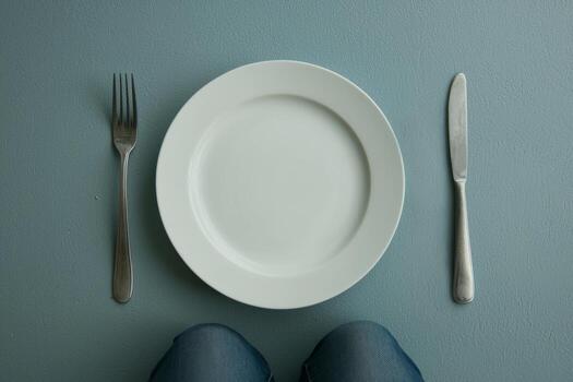 Empty white plate with fork and knife on a table photo