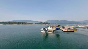 Canada Vancouver 12.09.2024 Seaplanes docked by a serene harbor with mountains in the distance. A calm harbor scene featuring seaplanes docked on the water, ready for takeoff. video