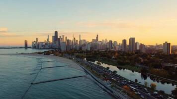 Chicago skyline and lakefront at sunset. Aerial view of the Chicago skyline with Lake Michigan and a busy highway along the lakefront, illuminated by sunset colors. video