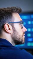 Futuristic Data Analytics Observation with Professional in Glasses Focused on Screen Displaying Digital Metrics and Insights, Blurred Blue Background, Modern Technological Analysis Concept photo