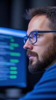 Focused IT Professional Writing Code on Computer Screen in Modern Office Setting, Highlighting Technology, Software Development, and Programming Expertise with Eyeglasses photo
