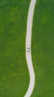 Aerial View of Car Driving on Winding Road Through Vast Green Landscape Expressing Tranquility and Freedom photo