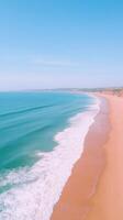 Vertical Aerial Drone View of Expansive Ocean Waves Washing Ashore on Sandy Beach Under Clear Blue Sky, Capturing Idyllic Coastal Scene, Perfect for Summer Travel, Nature and Relaxation Themes photo