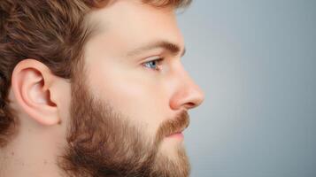 Profile View of Young Man with Stubble and Short Hair on Light Blue Background Highlighting Facial Hair Trend and Masculine Features photo