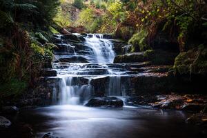 Waterfall cascading down rocks in autumn forest creating a beautiful landscape photo