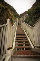 Steep metal staircase leading up a hill between green slopes photo