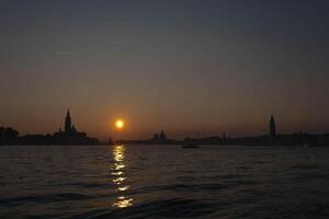 The sun is setting over the venice lagoon, creating a beautiful golden reflection on the water photo