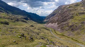Breathtaking view of a winding road through a green rocky mountain valley under a blue sky photo
