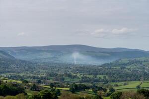 Expansive view of a misty green valley and rolling hills under a blue sky photo
