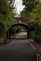 Low bridge warning sign over empty road passing under a railway bridge photo