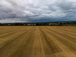 Harvested wheat field stretching towards distant town under cloudy sky photo