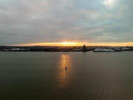 Orange sunset illuminating river mersey in liverpool with ferry docked photo