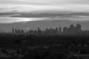 London skyline under construction with cranes and suburban houses in foreground at sunset in black and white photo