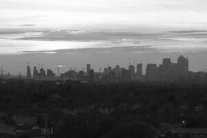 Canary Wharf emerging from the suburbs at sunset in black and white photo