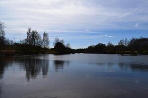 Calm lake reflecting trees and sky in spring photo