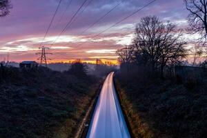 Plymouth Train speeding through Plymouth countryside at dawn under colorful sky photo