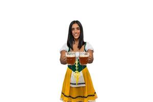 Smiling bavarian woman showing two cold beer glasses to camera in traditional oktoberfest attire photo