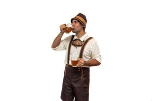 Young bavarian man drinking a beer glass while holding another in traditional oktoberfest attire photo