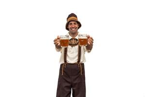 Smiling young bavarian man holding two beer glasses towards camera during oktoberfest photo