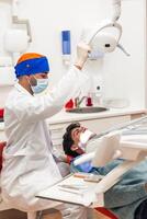 Dentist adjusting lamp while examining patient in clinic photo
