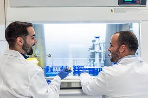 Two smiling male scientists working with test tubes in laboratory photo
