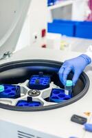 Scientist placing sample in laboratory centrifuge for testing photo