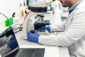 Scientist using microscope doing scientific research in laboratory photo