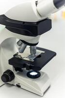 Modern microscope with light illuminating sample slide in laboratory setting photo