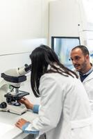 Scientists working together with microscope in laboratory photo