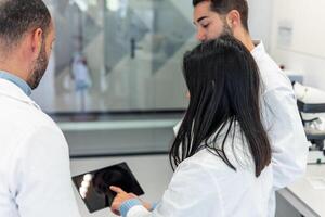Scientists using tablet in laboratory discussing research photo
