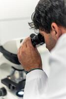 Scientist looking through a microscope in a laboratory photo