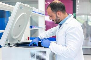 Scientist placing samples in laboratory centrifuge for research photo
