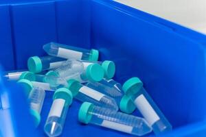 Empty test tubes with green caps lying in blue container in laboratory photo