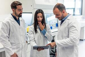 Scientists looking surprised at the results on a tablet in laboratory photo