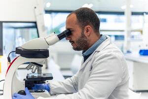 Scientist using microscope in bio modern laboratory performing scientific research photo