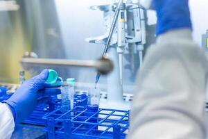 Scientist adding blue reagent to test tubes using micropipette in laboratory photo