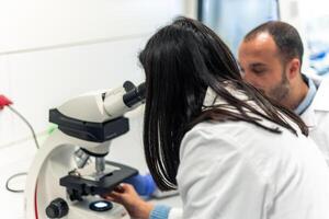 Scientists working with microscope in laboratory photo
