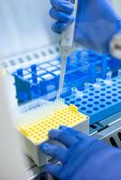 Scientist using a micropipette dropping liquid into a micro test tube during medical research in a scientific laboratory photo