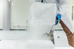 Scientist handling dry ice block in laboratory wearing gloves photo