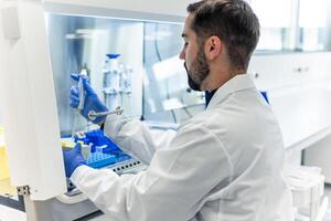 Scientist performing experiment using micropipette in laboratory photo