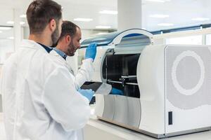 Laboratory technicians working with modern automated equipment in medical lab photo