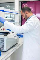 Scientist using laboratory centrifuge for research in modern laboratory photo